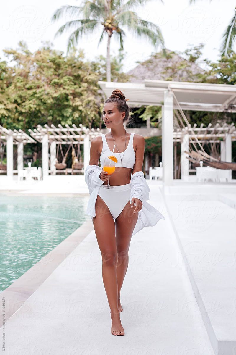 Cheerful woman with mimosa cocktail near pool