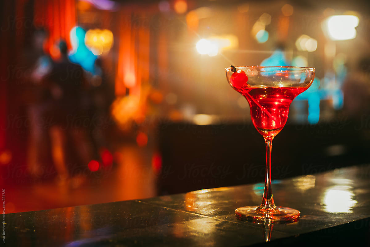 One Cherry sits in a Cocktail glass in a dark bar