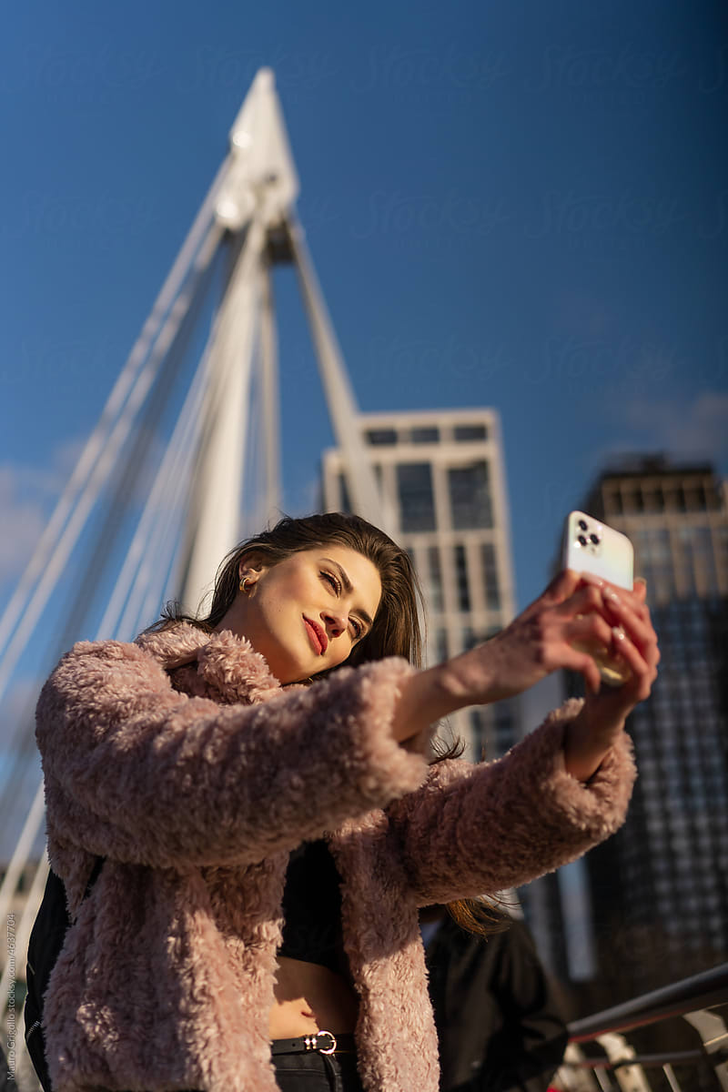 A woman uses a smartphone for a self-portrait in the city