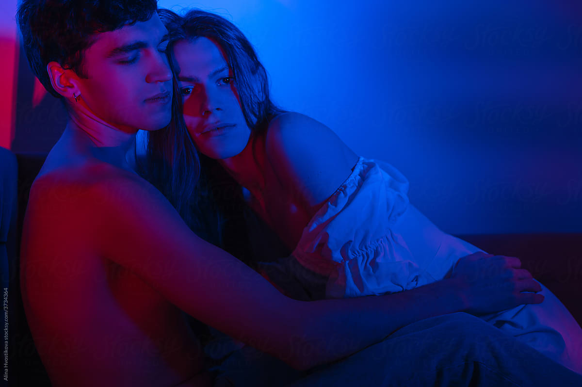 Couple lying together on sofa in room with neon lights