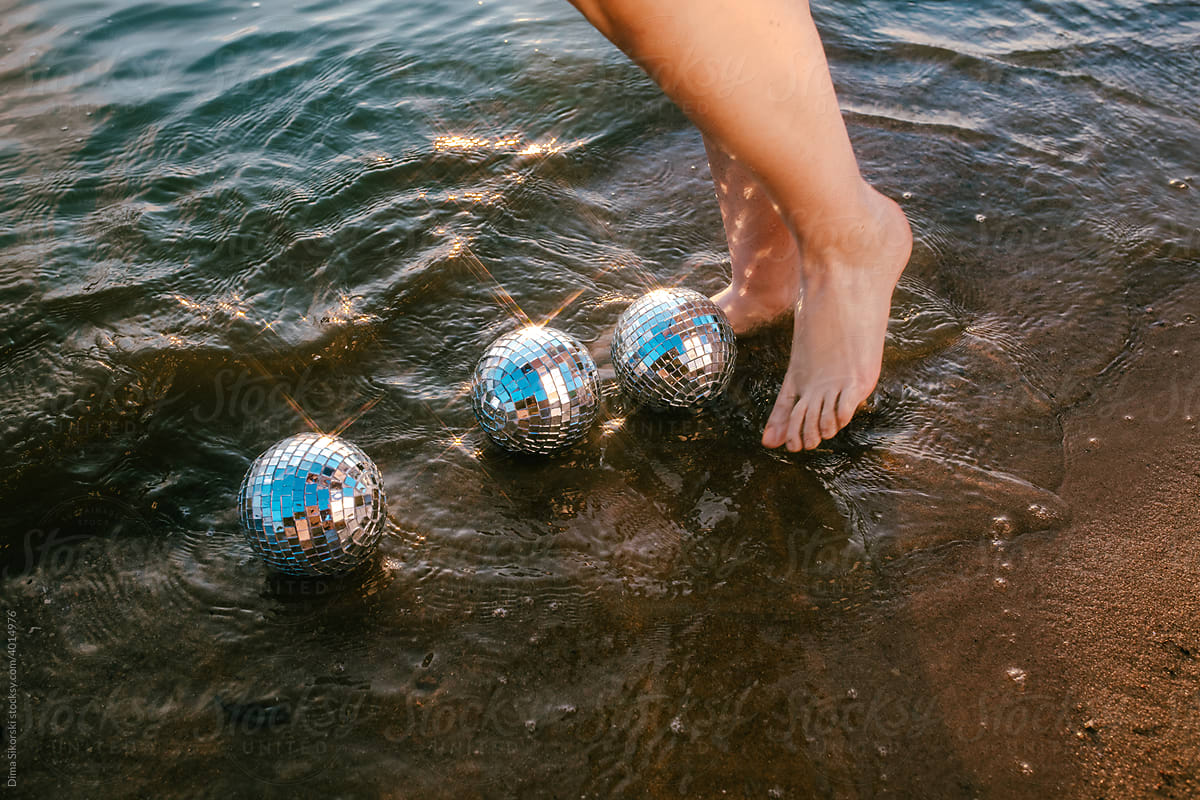 feet in the sea with mirror balls