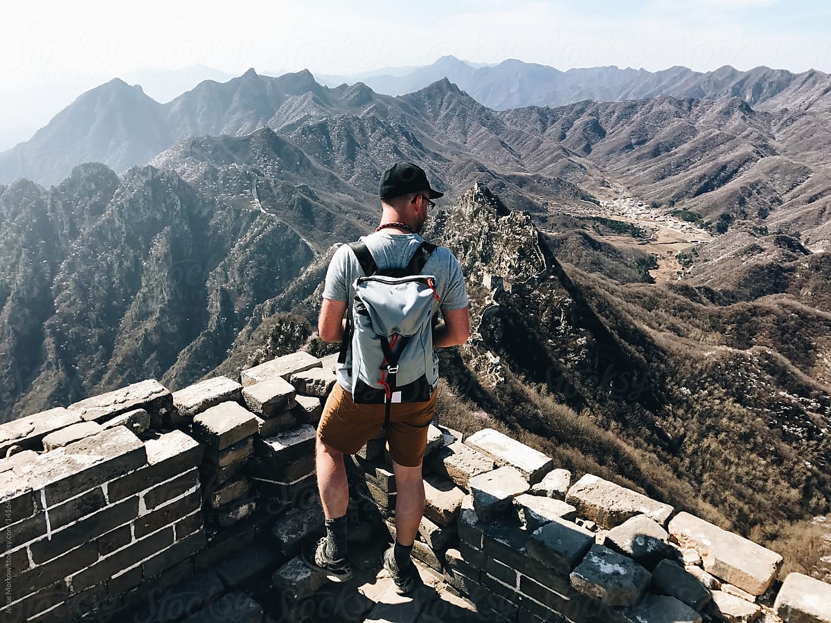 Young Man With Backpack Looking Out At Beautiful Landscape Scenery While Trekking Remote Areas Of The Great Wall Of China By Jesse Morrow Great Wall