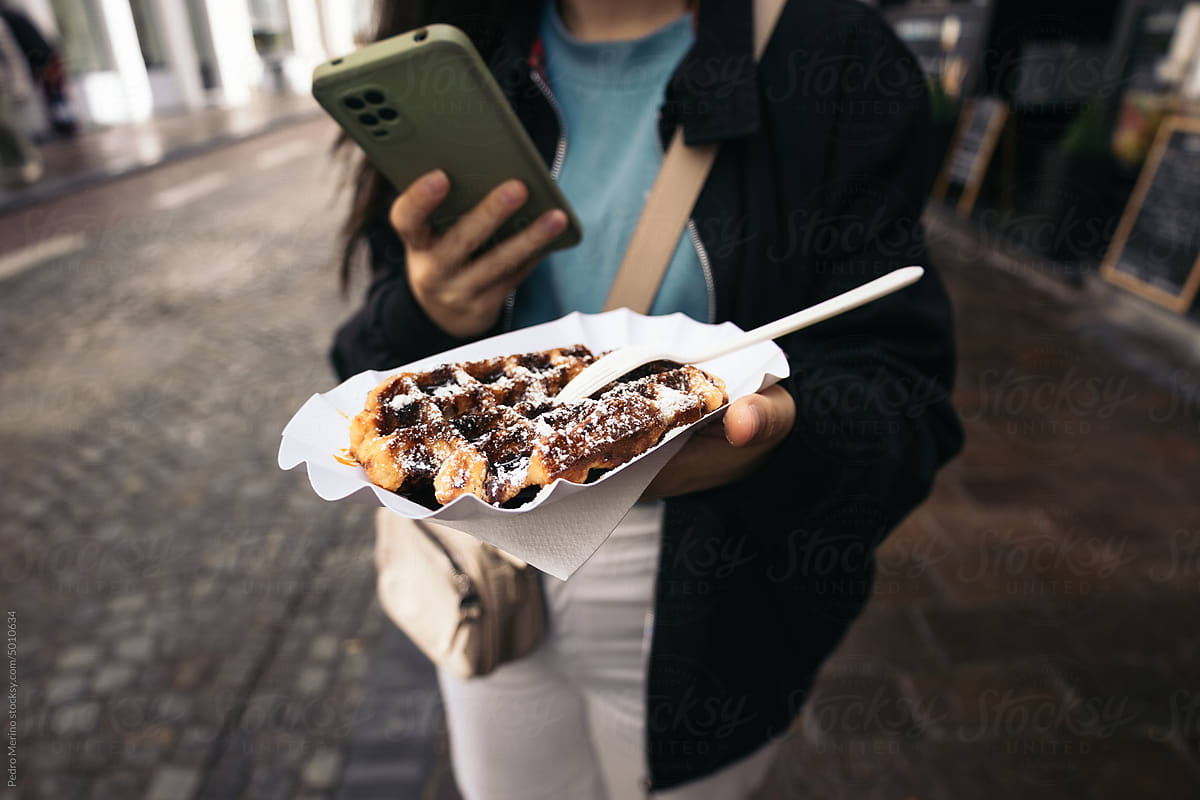 Woman taking a smartphone photo of a waffle in Belgium