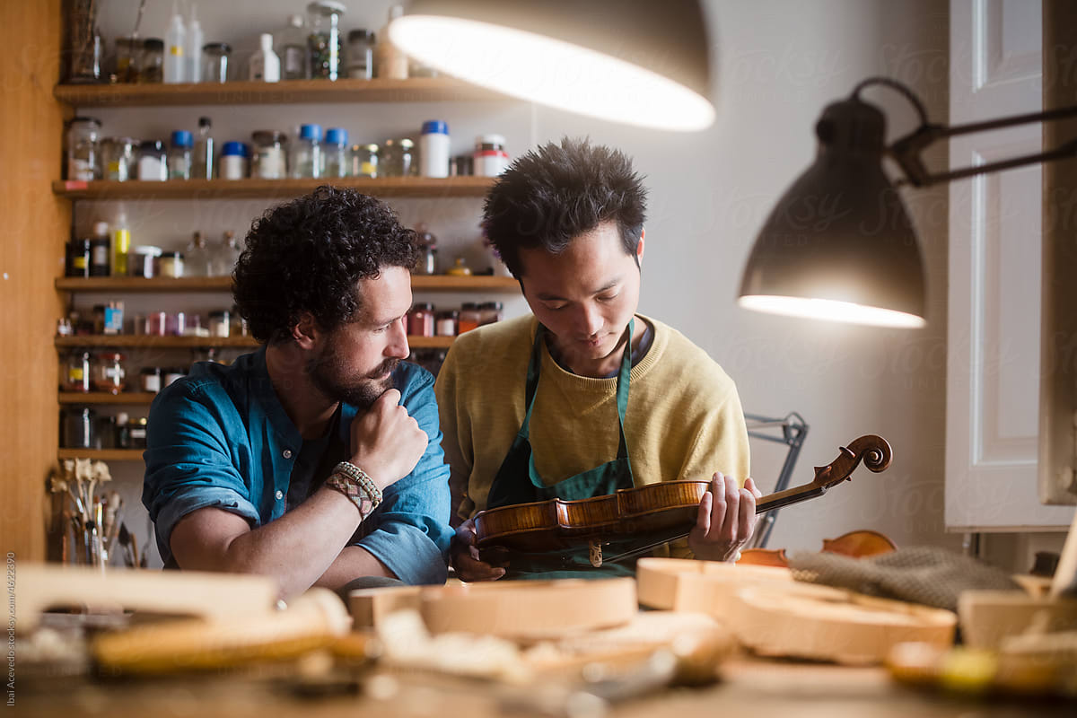 Fiddle luthiers examining an instrument at studio