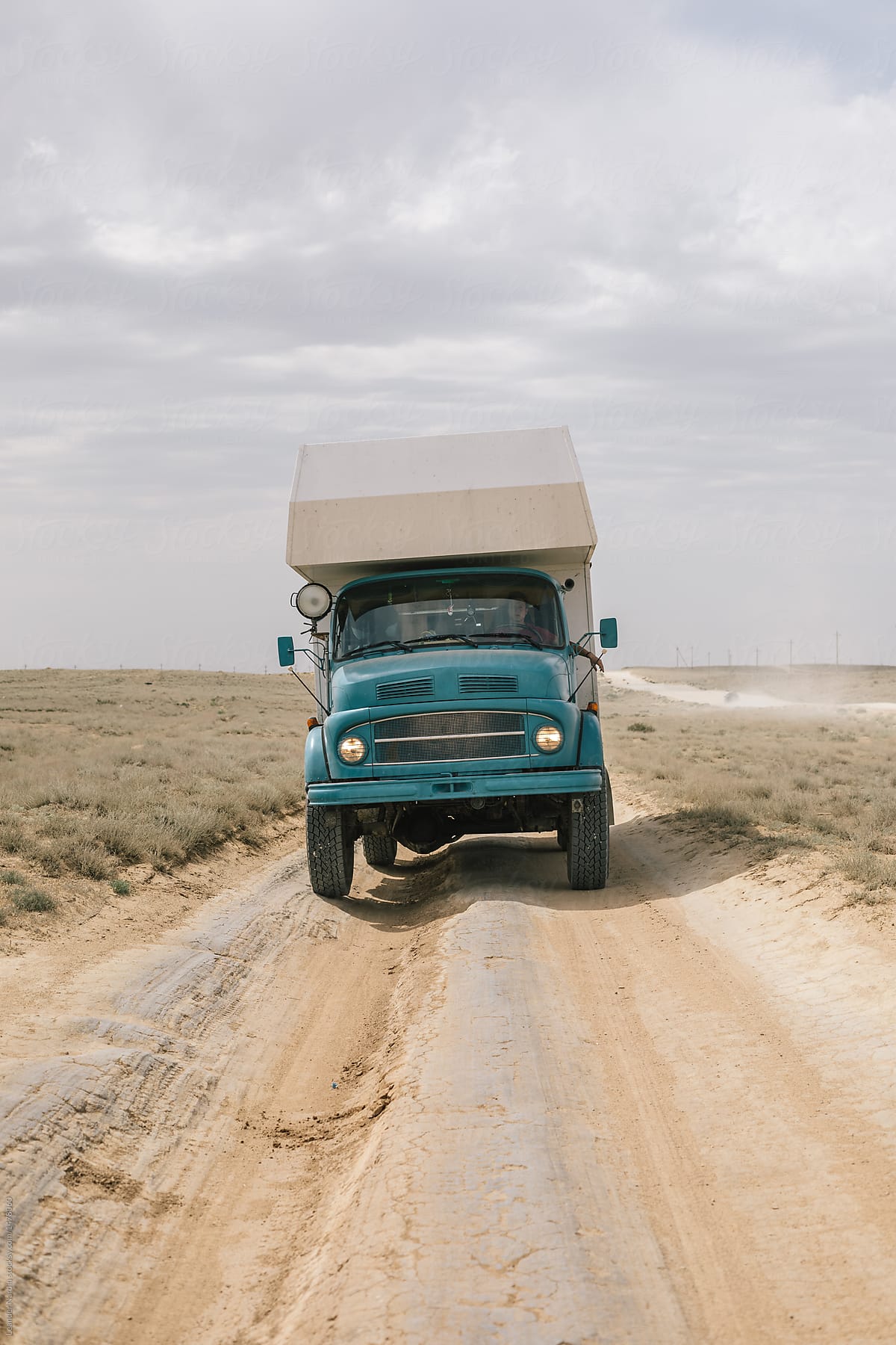 blue camping truck on sandy dirt road