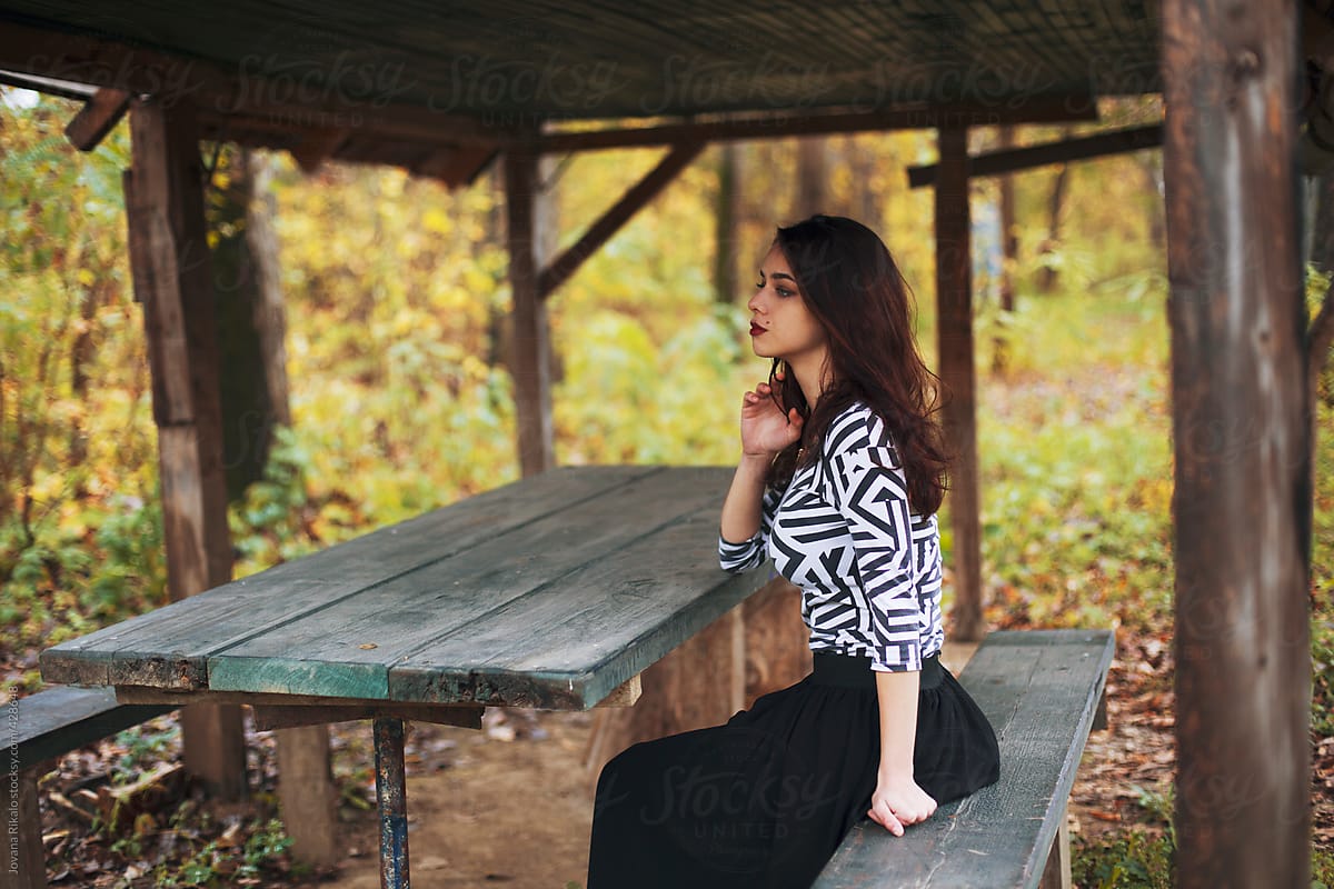 Young woman sitting in a forest bench
