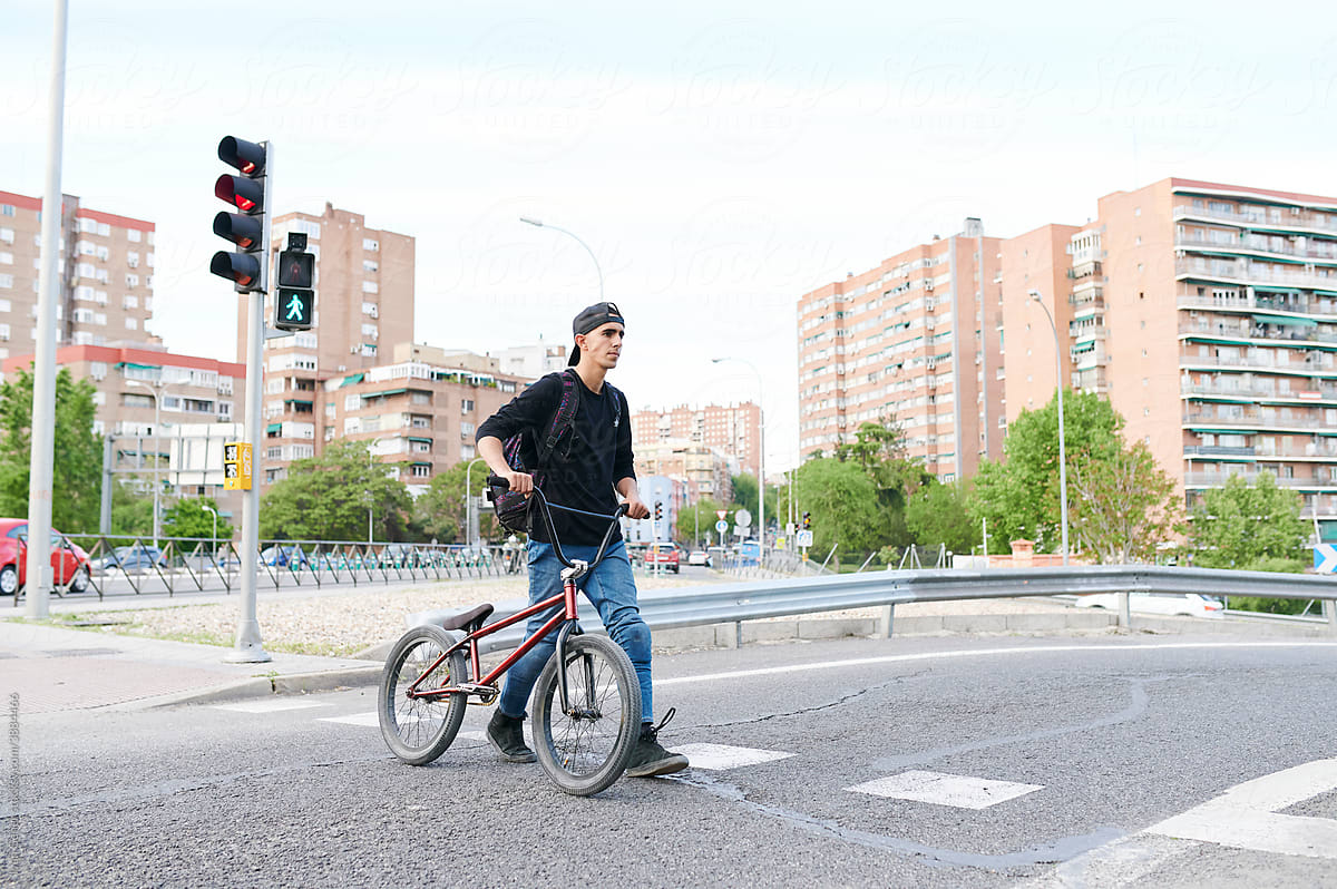 Young man crossing a street with his BMX bike