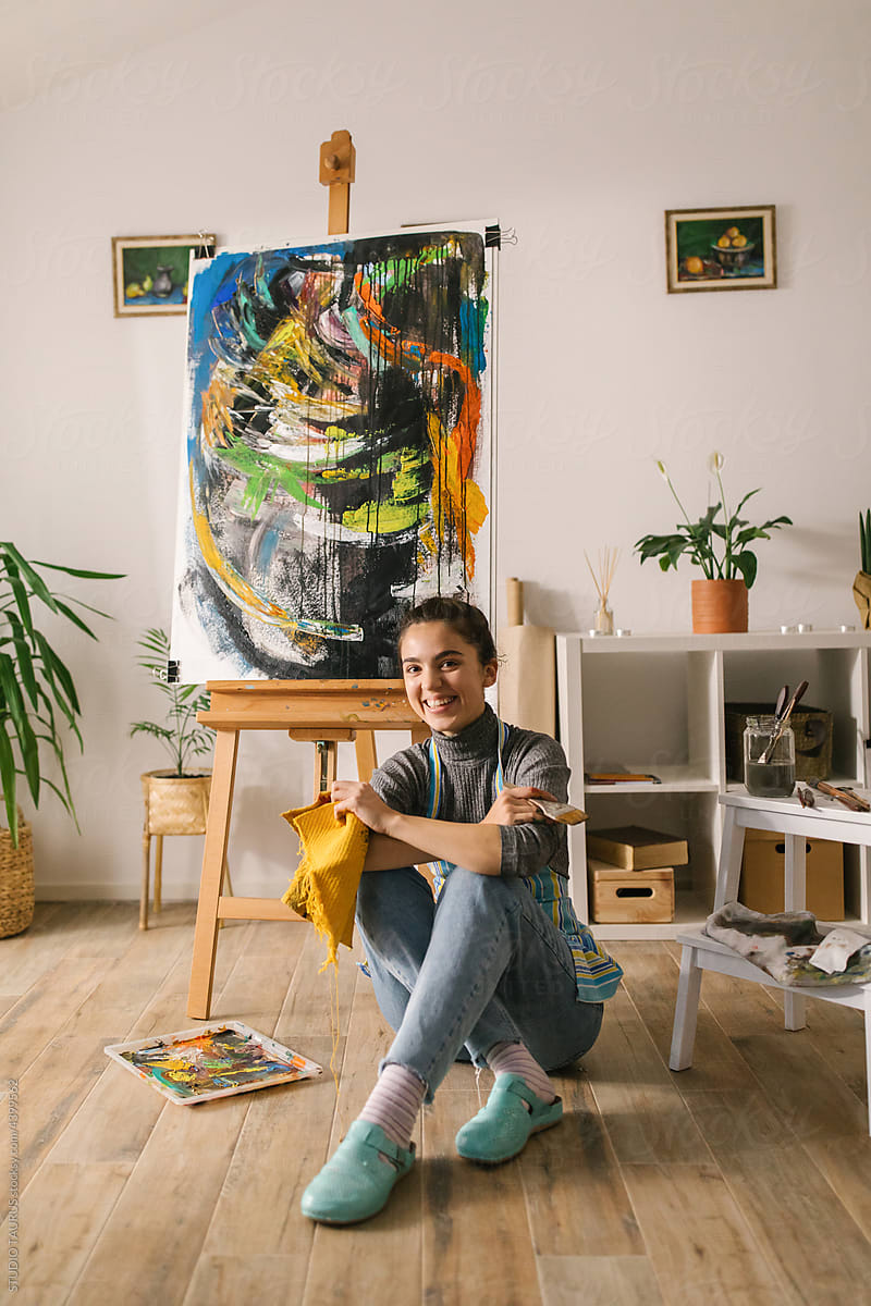 Portrait of happy artist posing with her painting