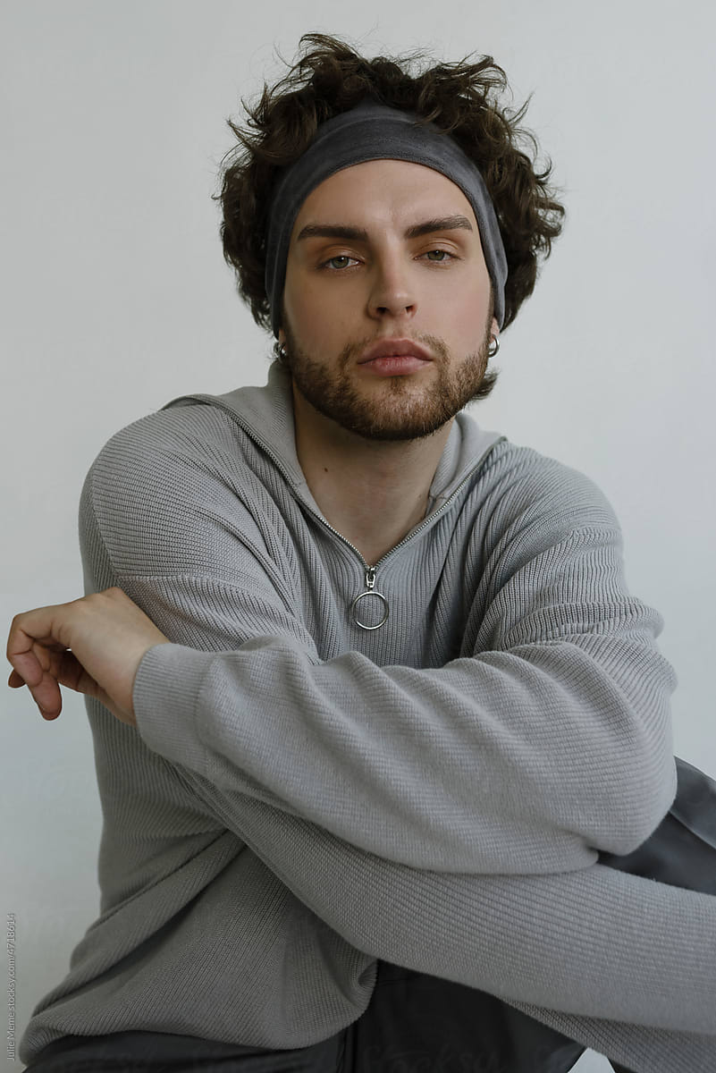 Stylish guy with a haughty face in a grey sweater and a headband