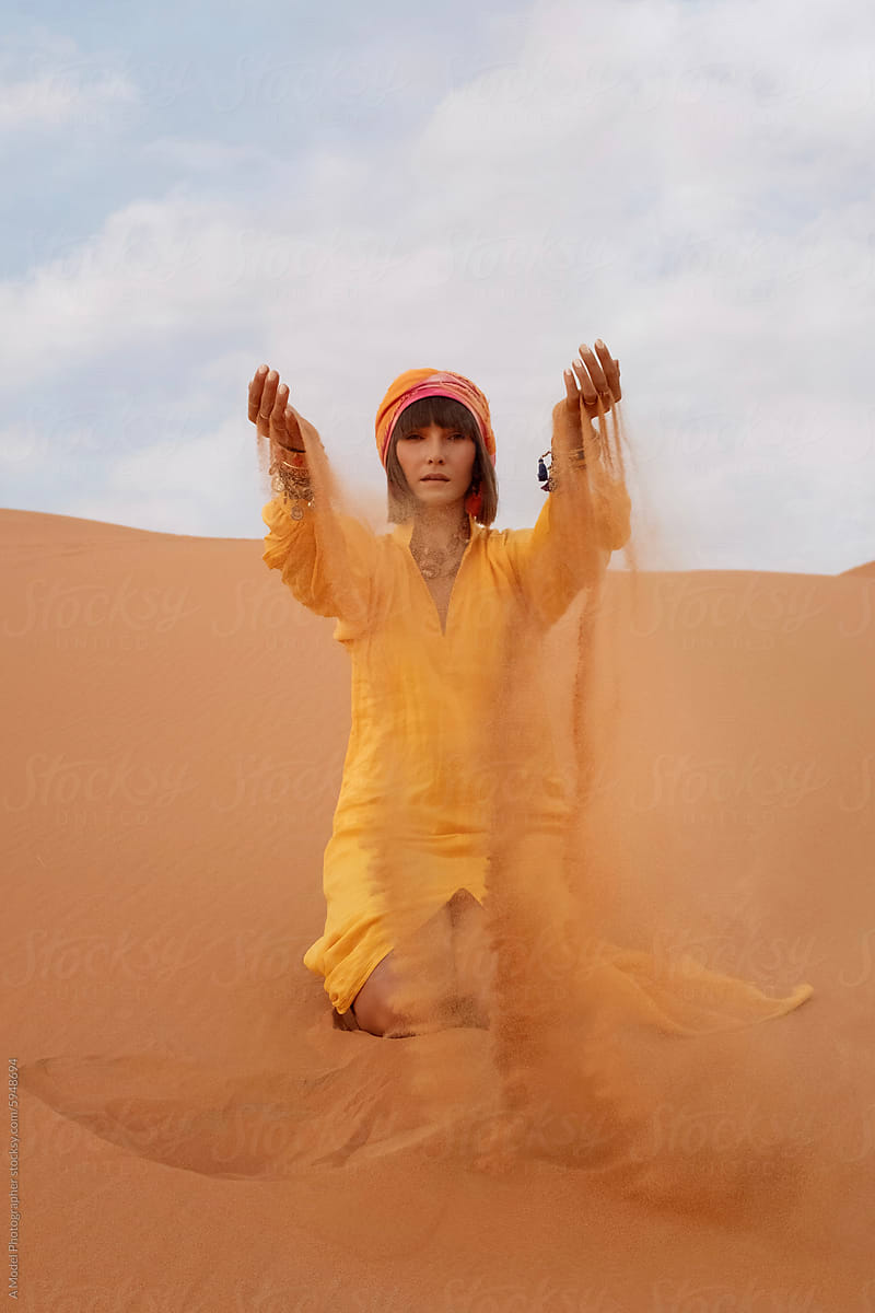 A woman in an Arabic-style outfit posing in the desert