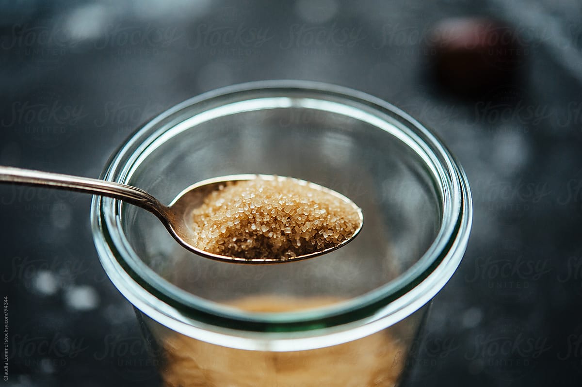 Heap Of Brown Sugar Sugar Placed On A Silver Spoon Above A Sugar Container  by Stocksy Contributor Claudia Lommel - Stocksy