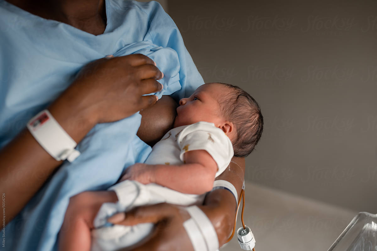 Crop black mother breastfeeding baby in ward