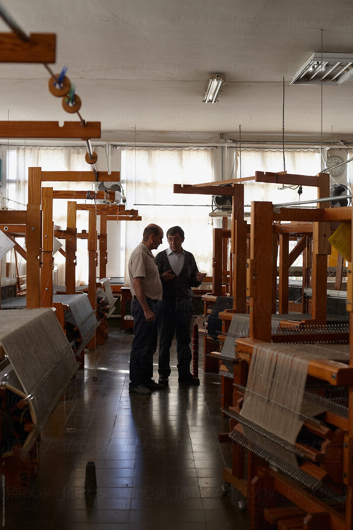 Two craftmen talking in a workshop of artisanal looms