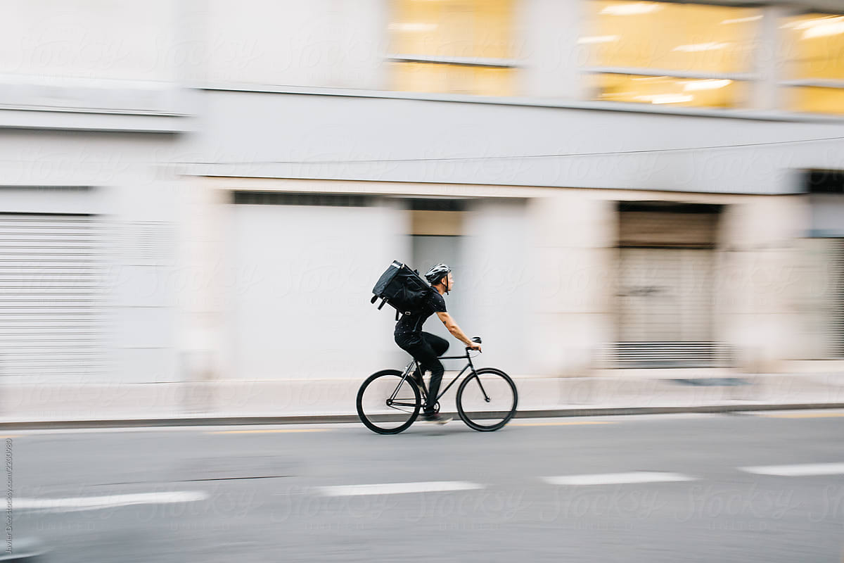 Man with delivery bag riding bycicle fast