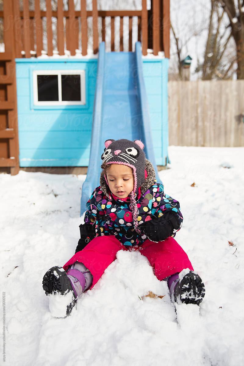 Toddler using a playground slide during winter