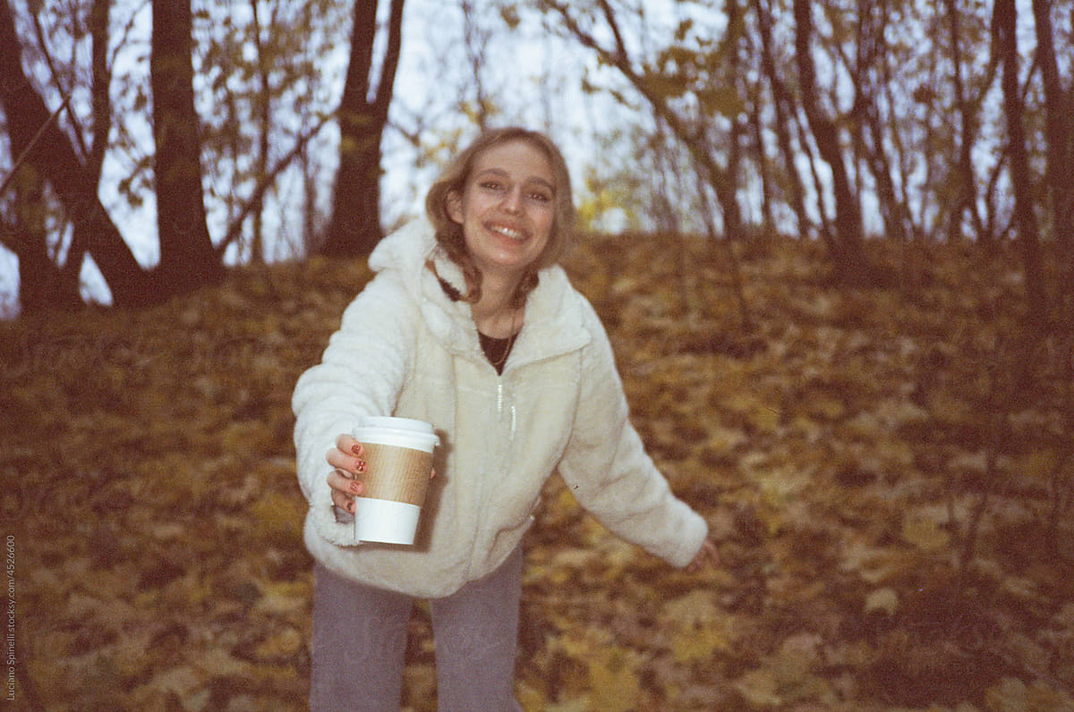 Girl walk in the forest holding a white cup
