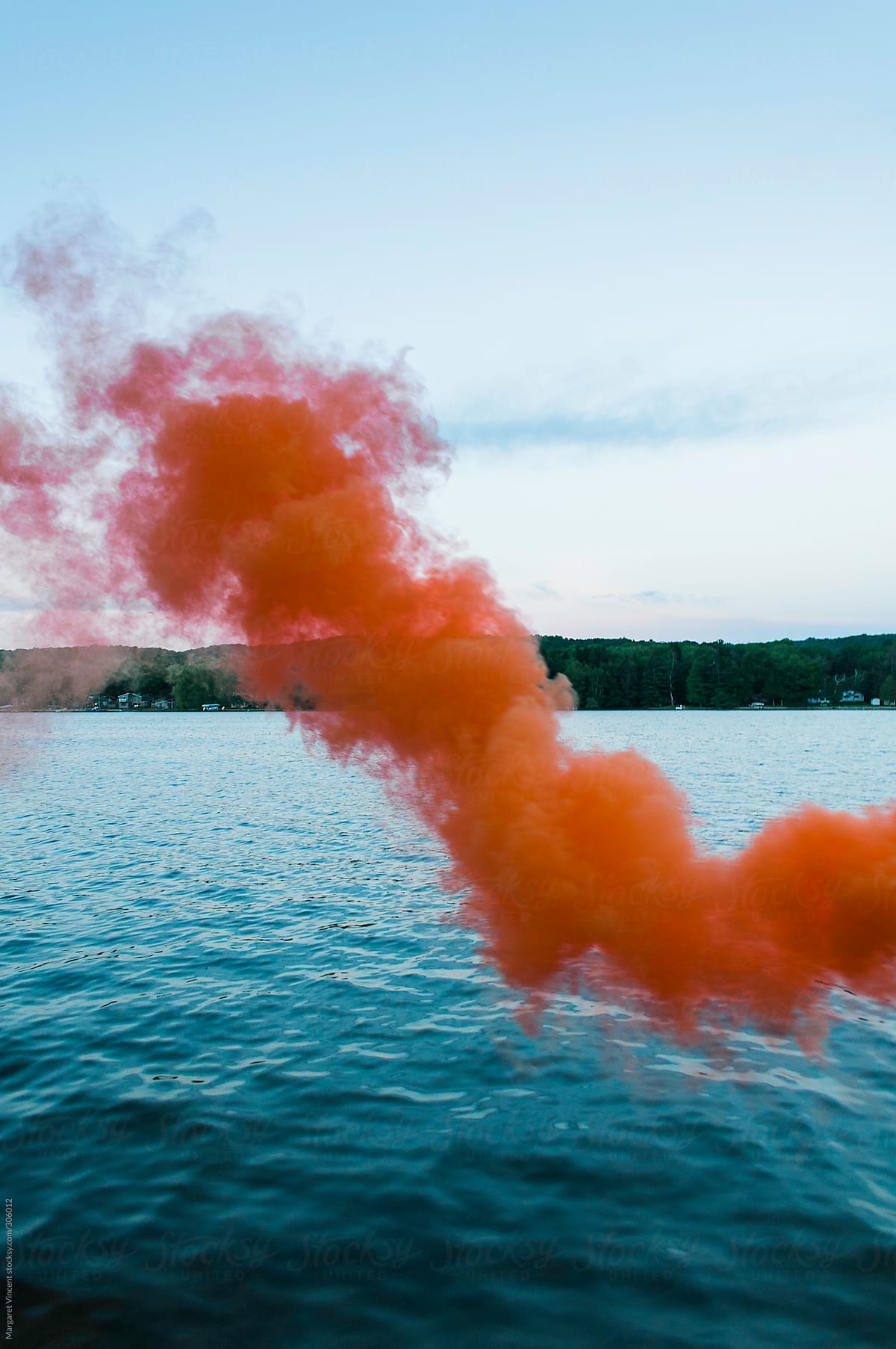 orange smoke bomb over blue lake