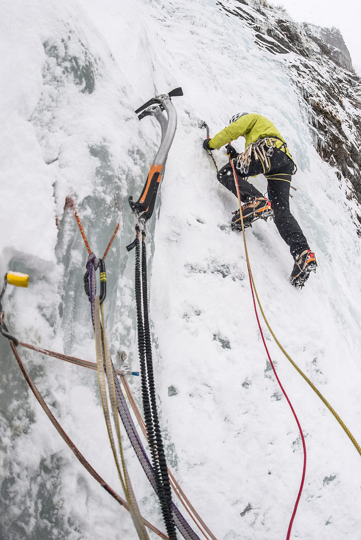 Alpinist ice climbing a steep frozen waterfall