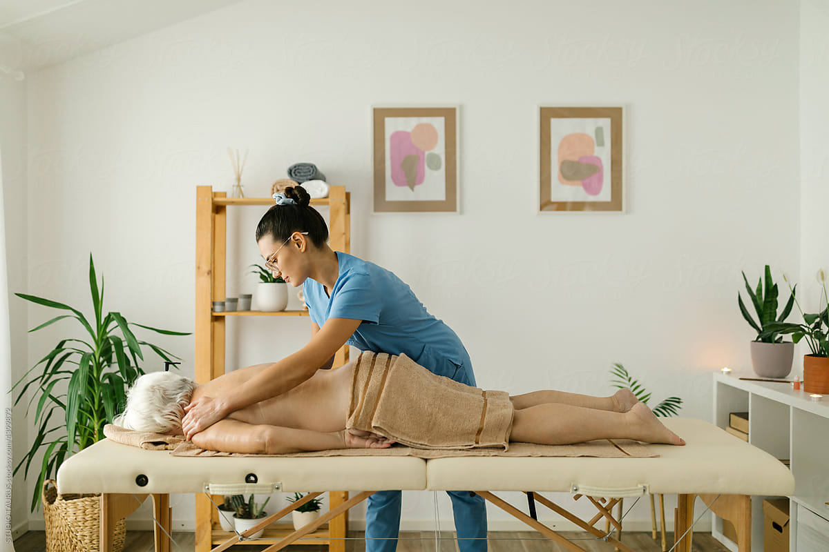 Massage therapist with a senior lady at spa