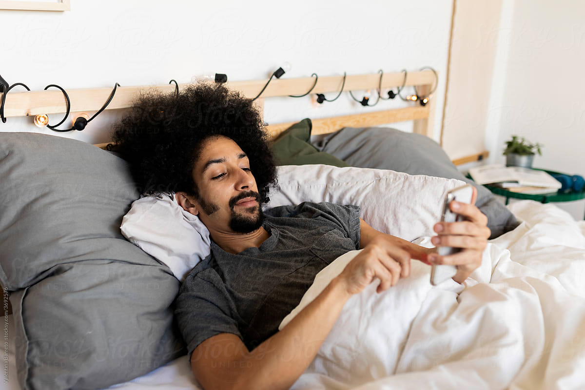 man using smartphone during morning time at bed