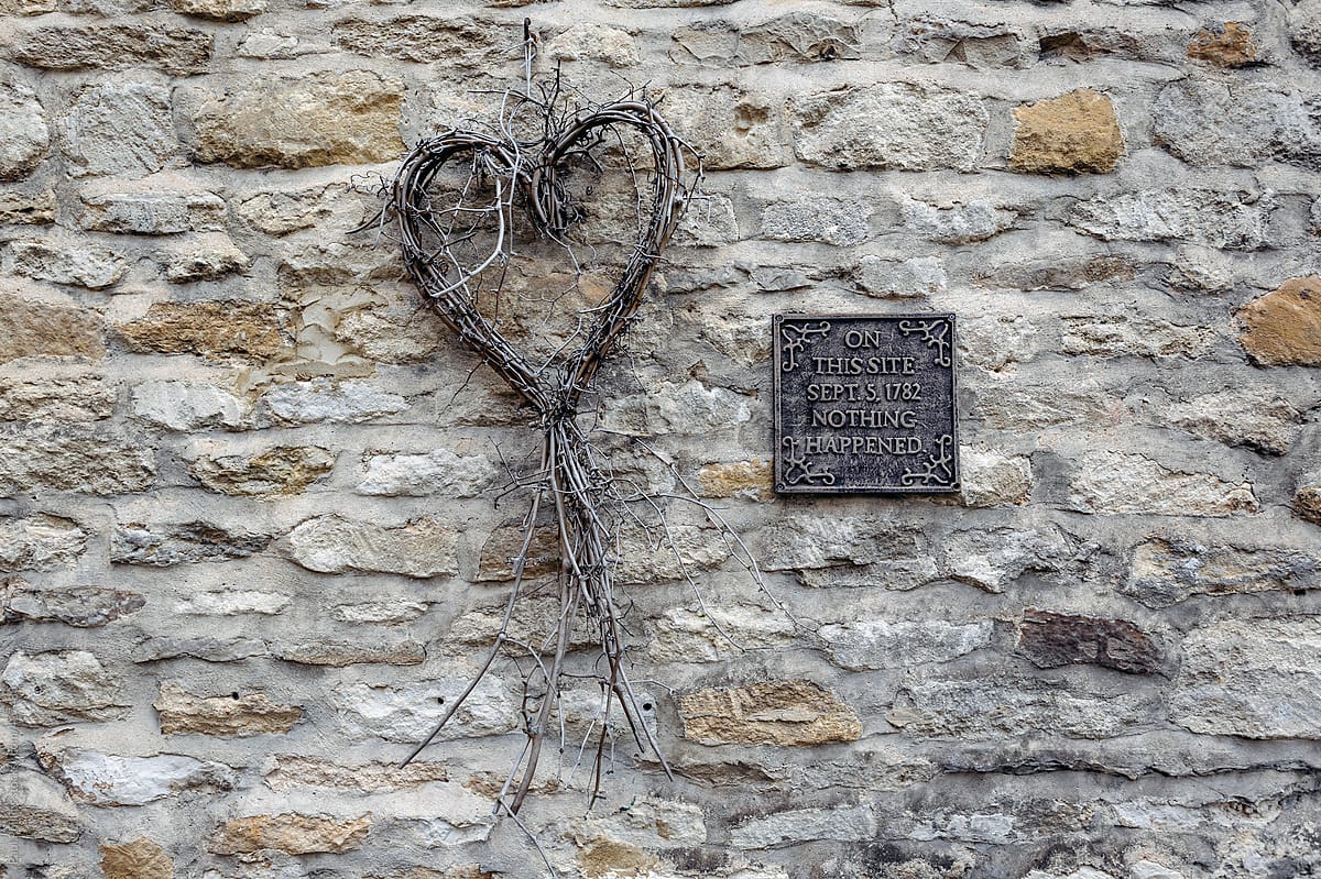 Heart made of twigs and a metal plaque with a message against a wall