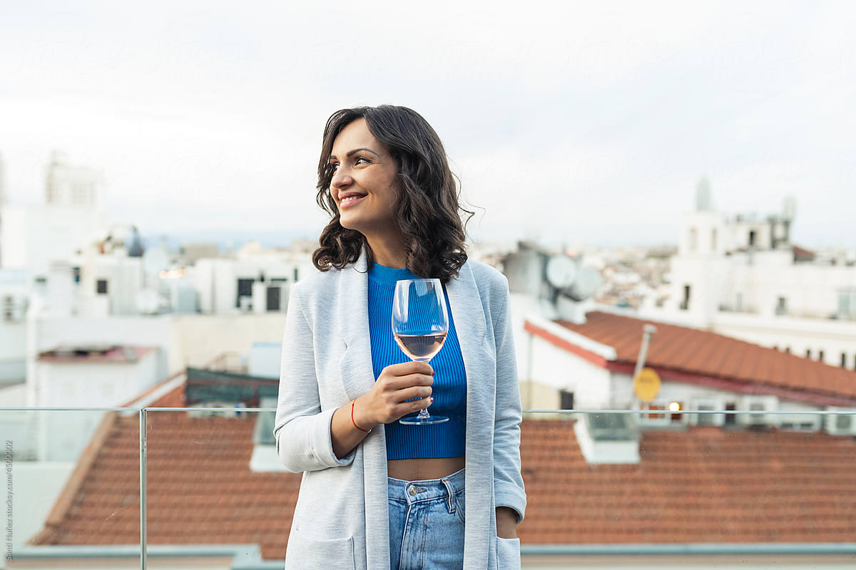 Smiling woman with glass on wine on terrace