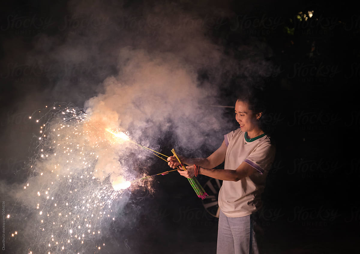 Asian woman, playing fireworks outdoors at night in nature