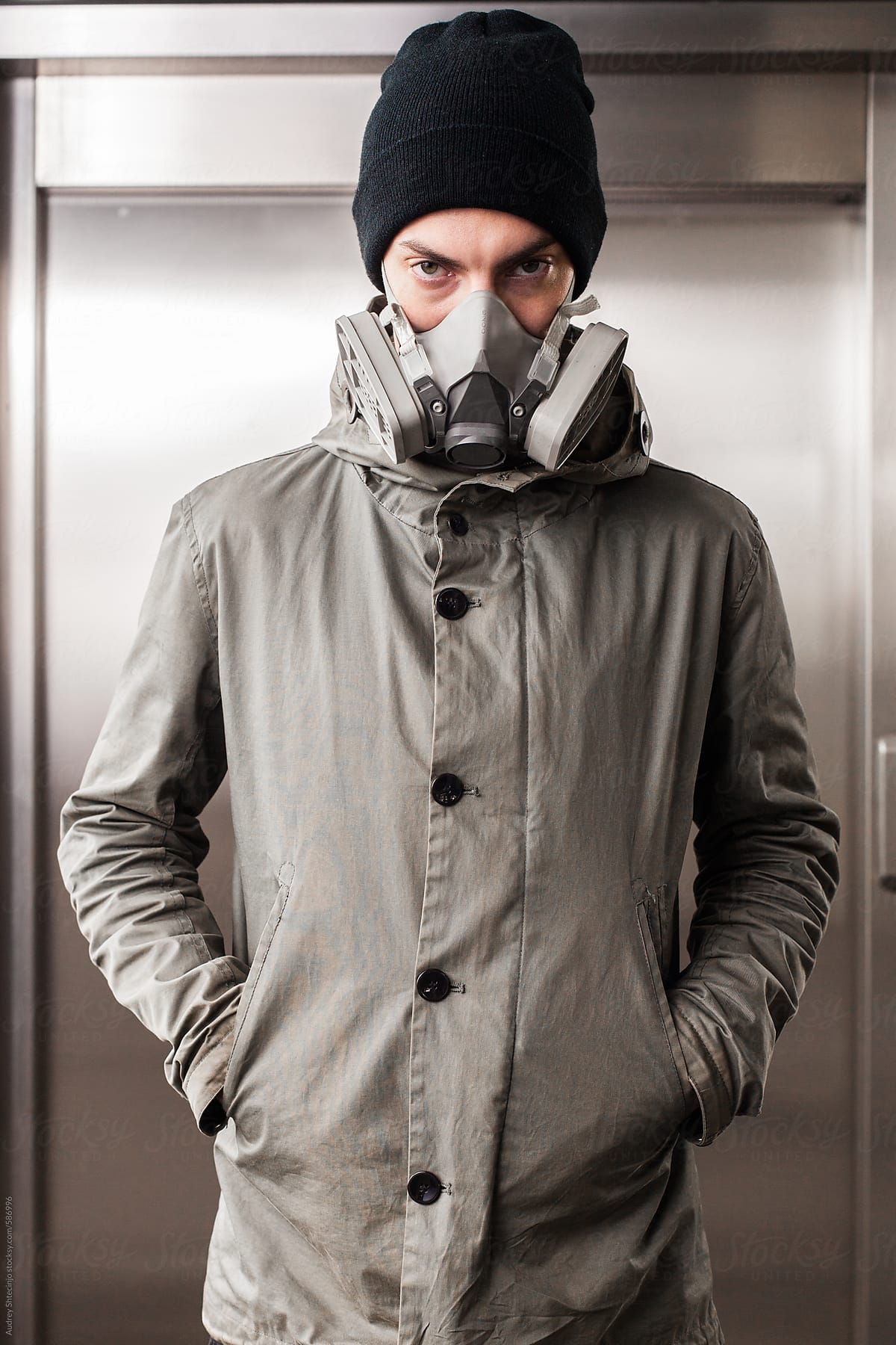 Portrait of male in urban outfit with graffiti mask.