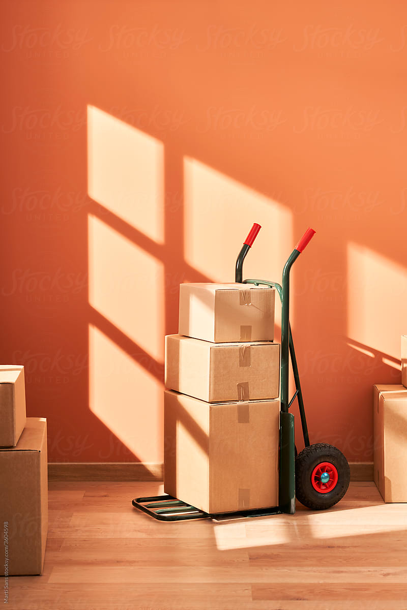 Cart with cardboard boxes against orange wall