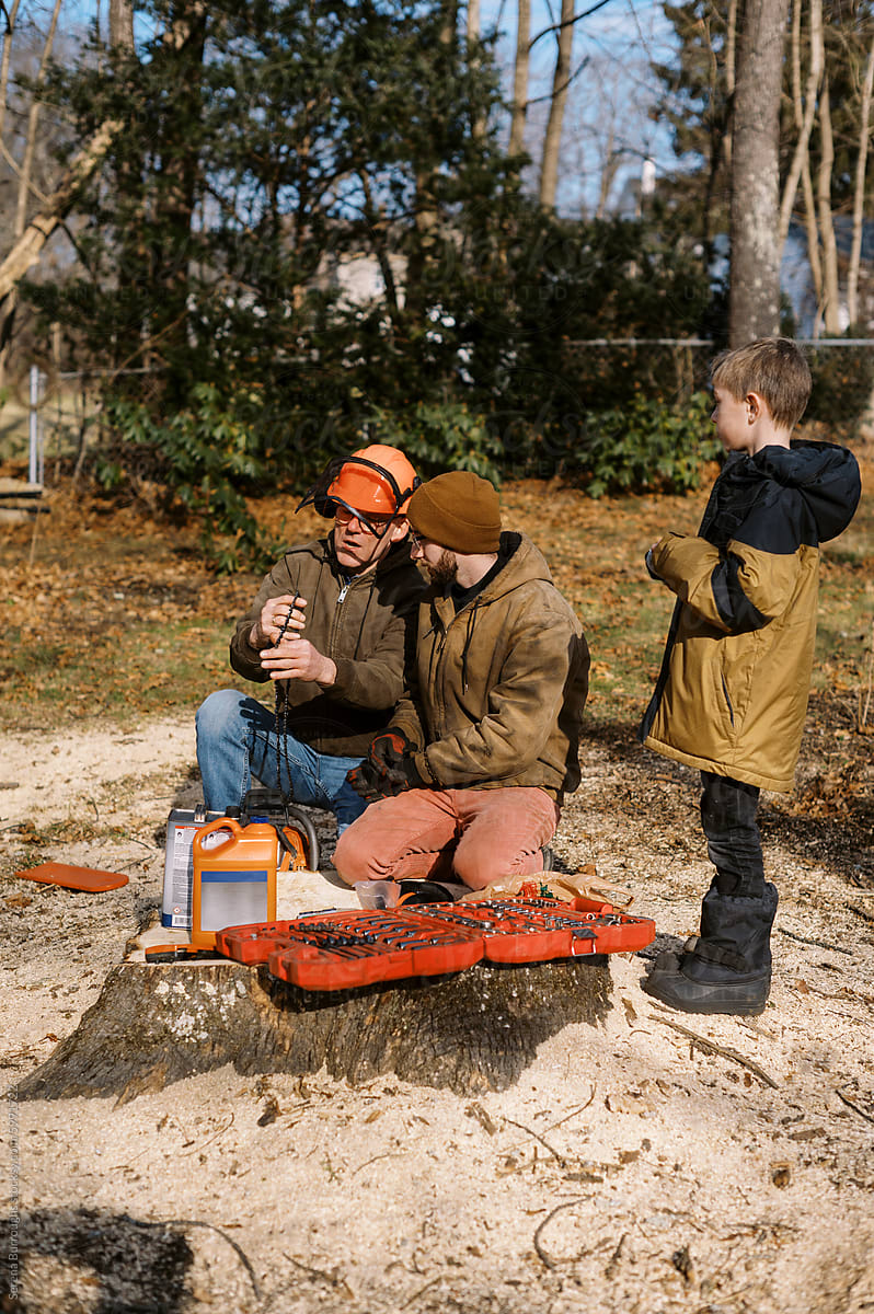 middle aged man teaching adult family member about chainsaw care