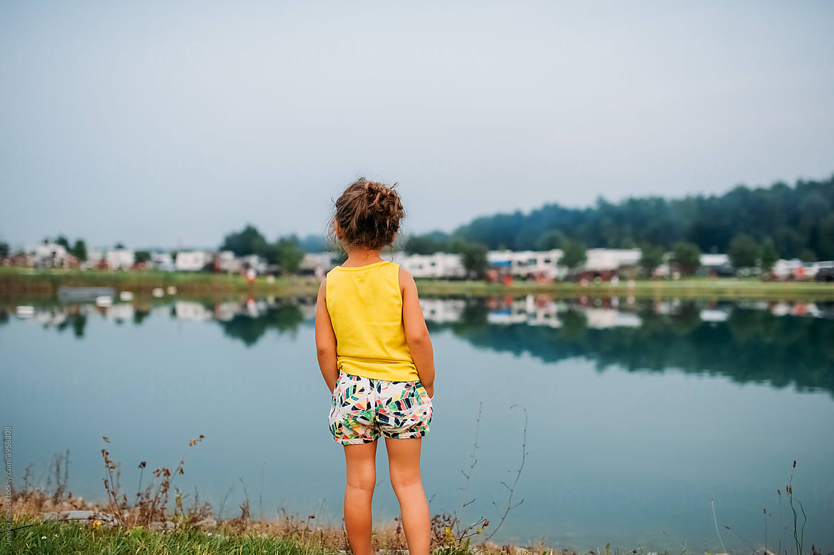 Child with their back to the camera looking at the lake.