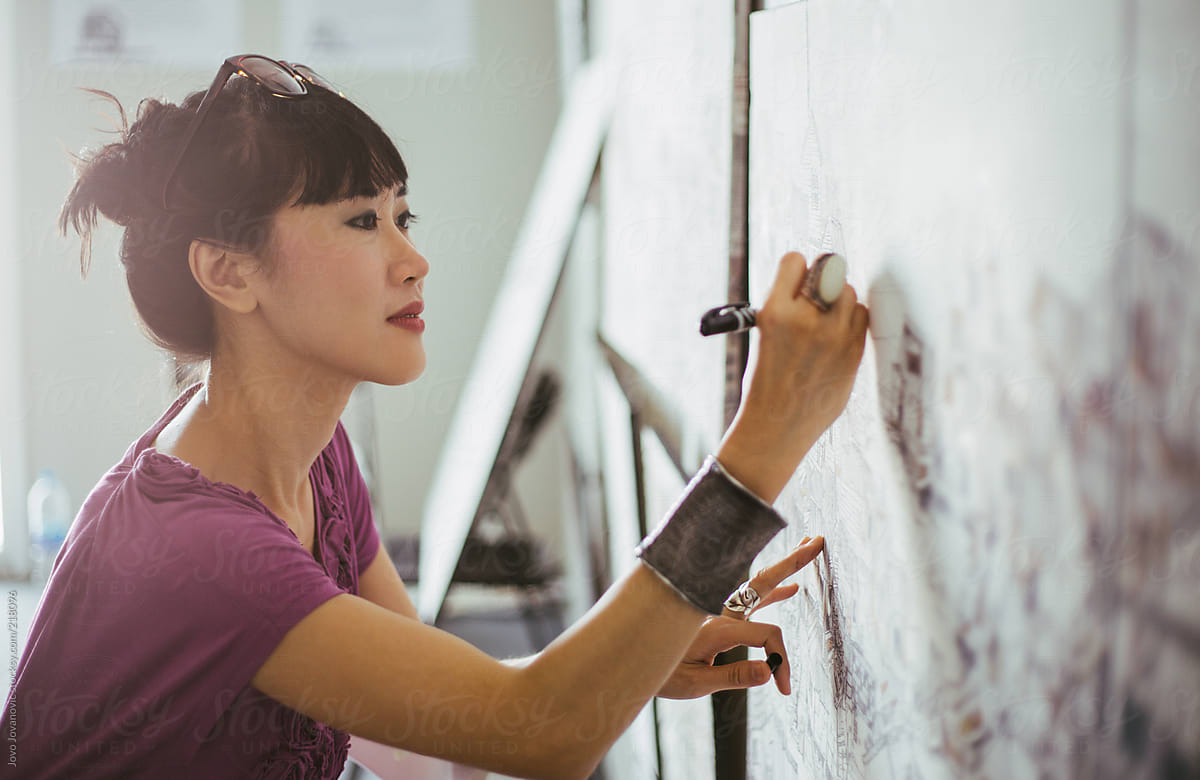 Side view of asian woman artist drawing on canvas