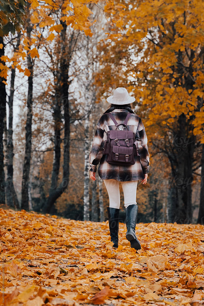 Fall adventurer: Woman with backpack walking among vibrant leaves