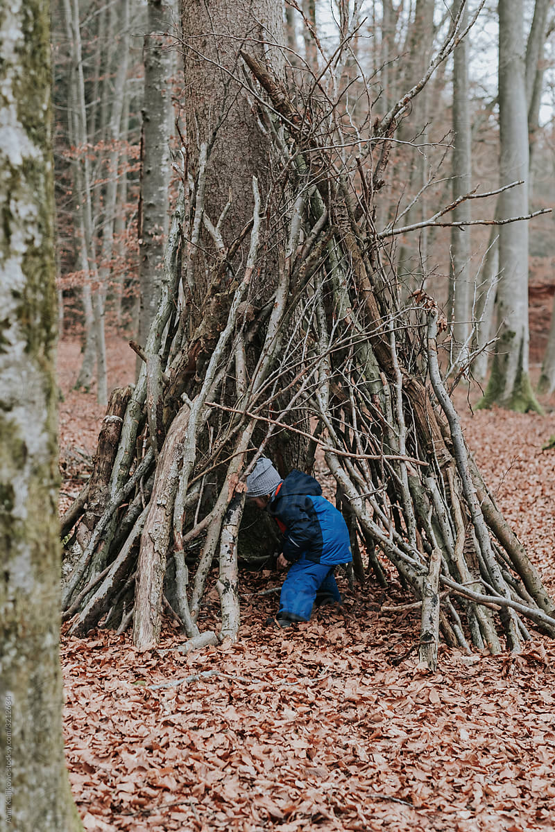 Small child playing in a wigwam in a forest