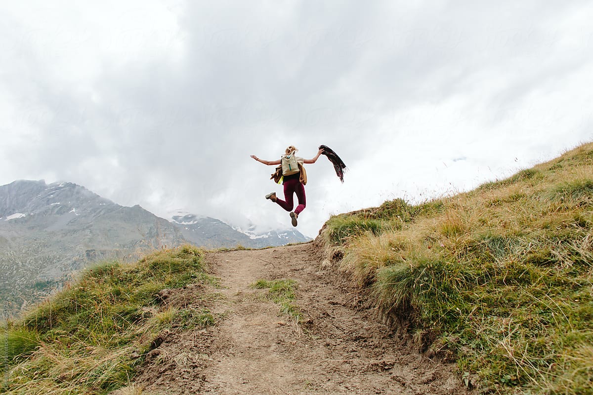 Happy woman jumps up in the mountains.