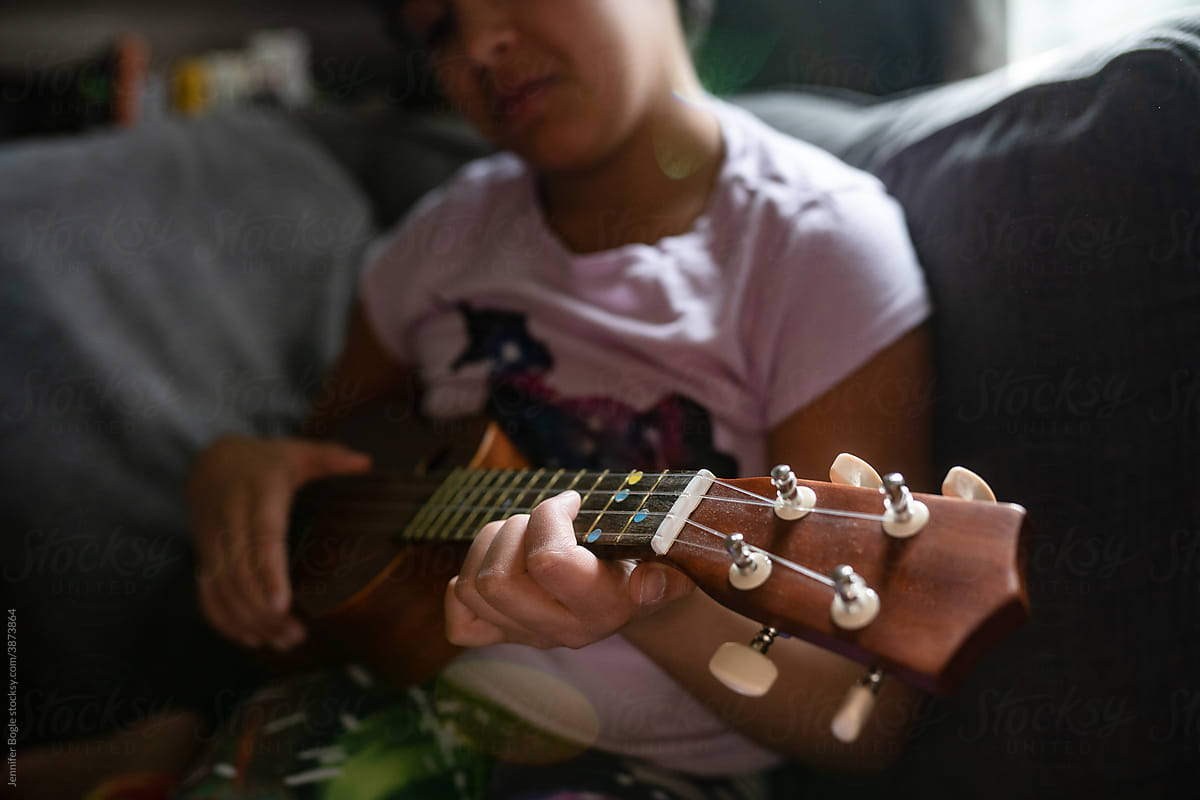 closeup of fretboard of girl playing ukulele