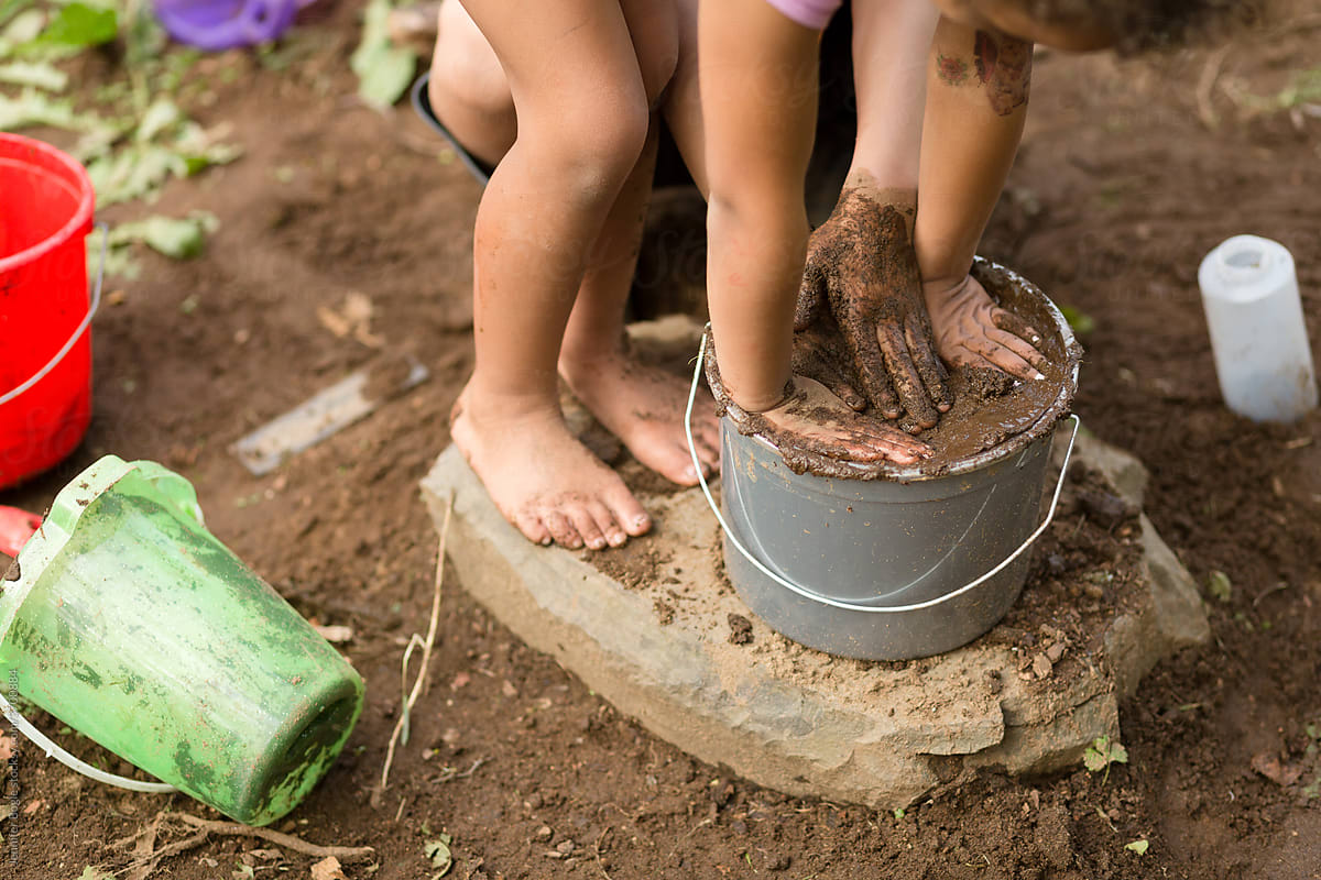 Barefoot children with bucket of mud