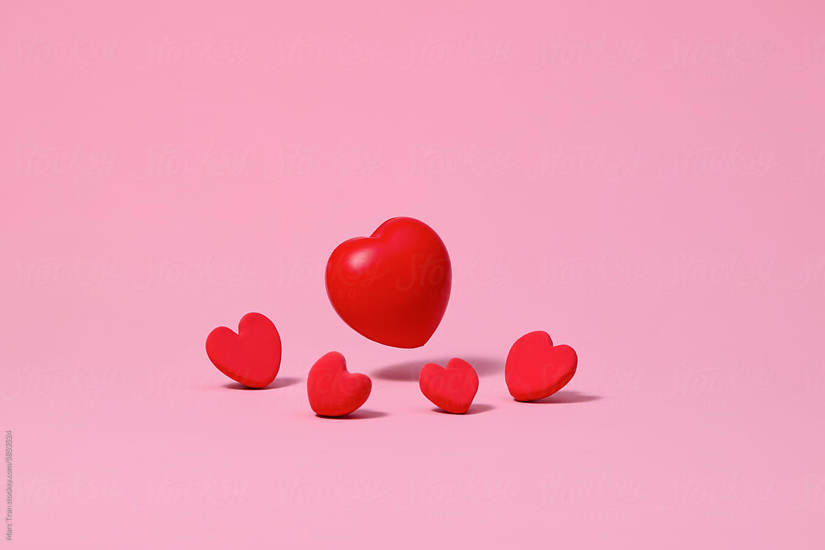 Five abstract red hearts made of clay on a pink background