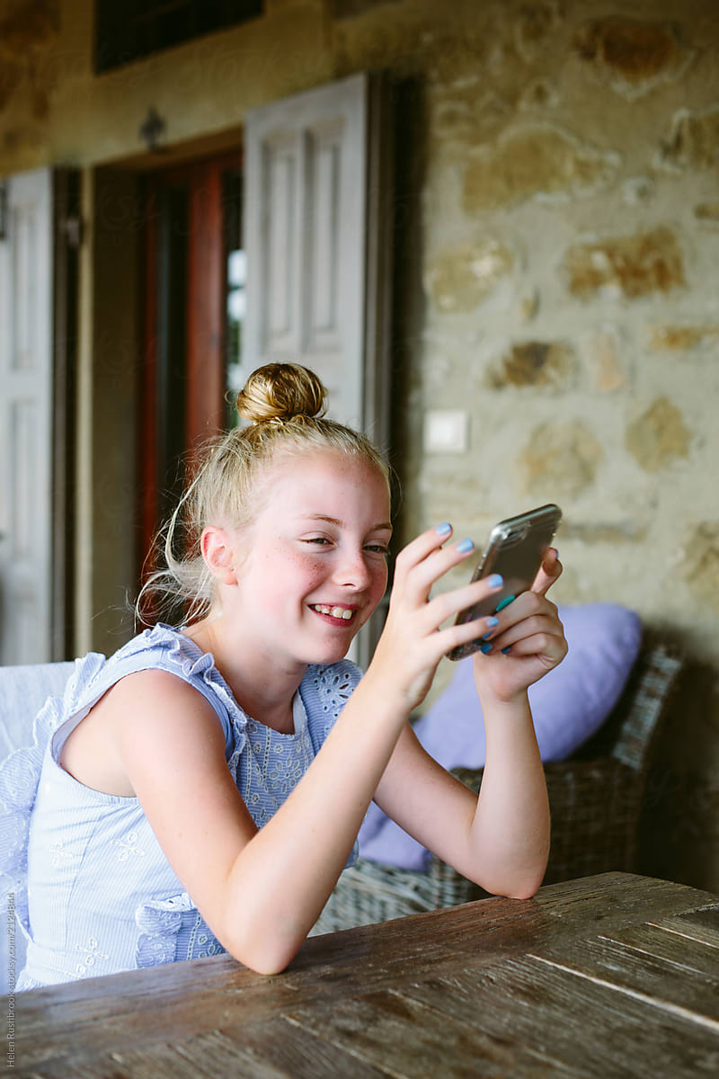 Preteen Girl Laughing While Holding Her Mobile Telephone By Stocksy Contributor Helen 