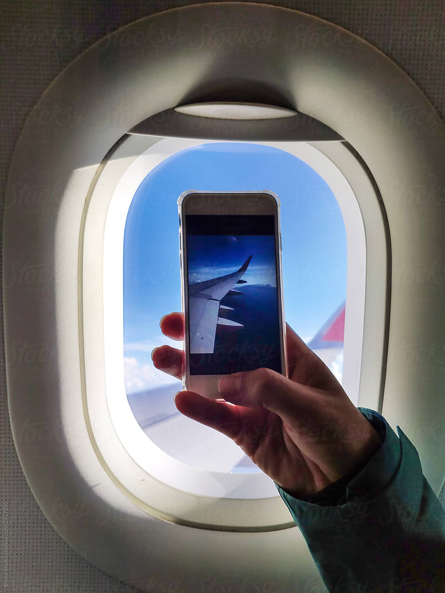 Man taking a picture through an airplane\'s window
