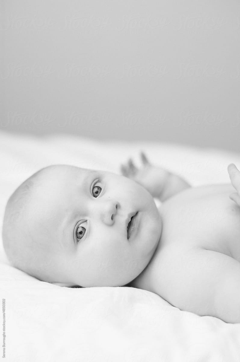 Portrait of a baby in a diaper on a bed with white sheets