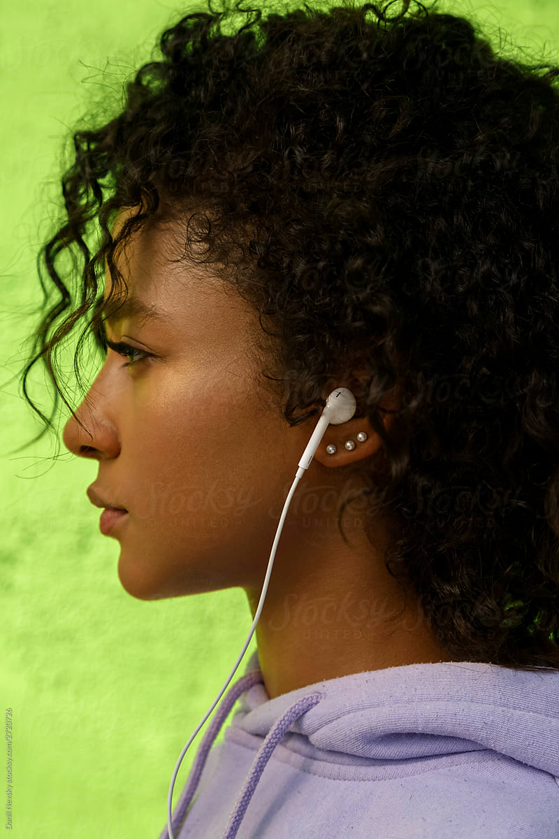 Attractive black woman in earphones standing on street