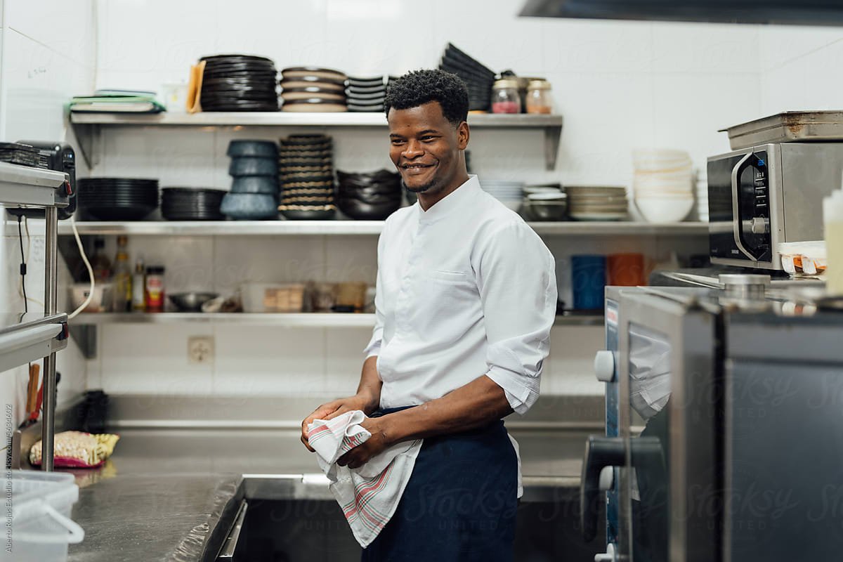 Cheerful cook with towel at work in restaurant