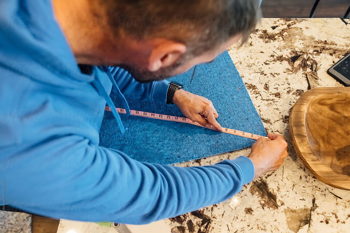 Man making measurements on blue material.