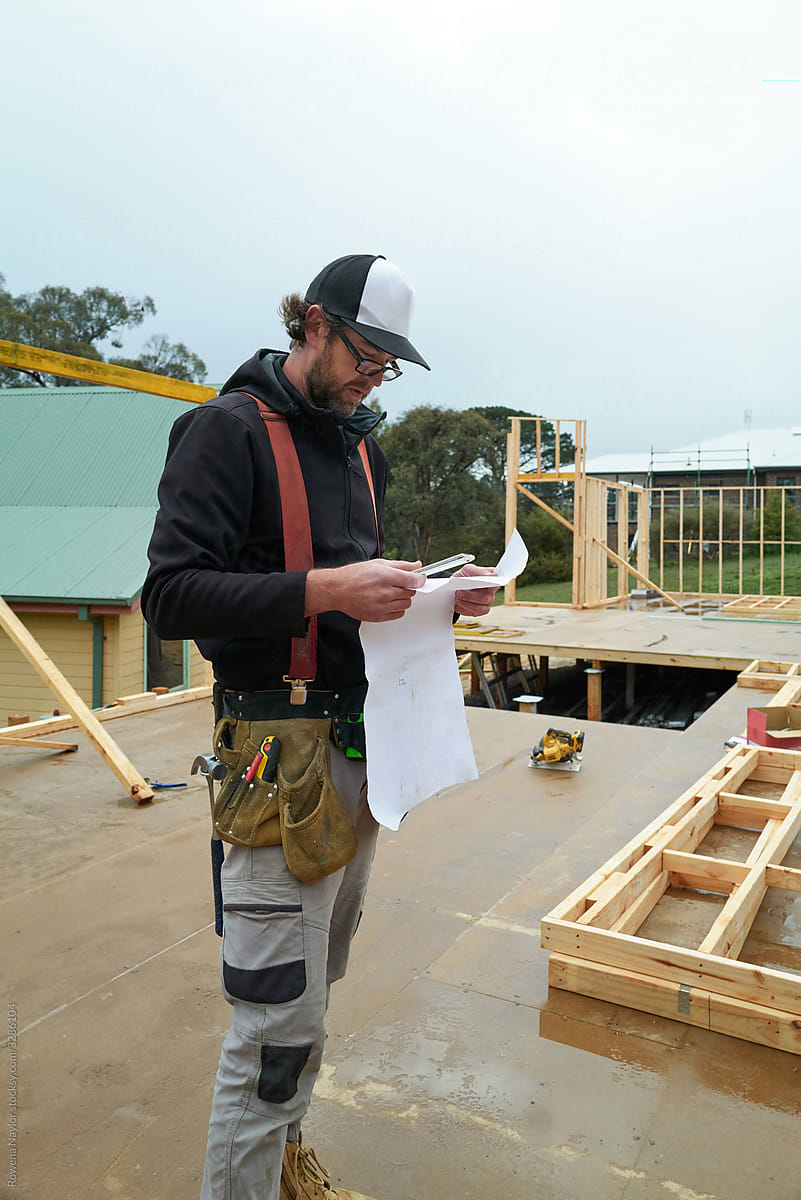 Builder reading architectural plan on worksite