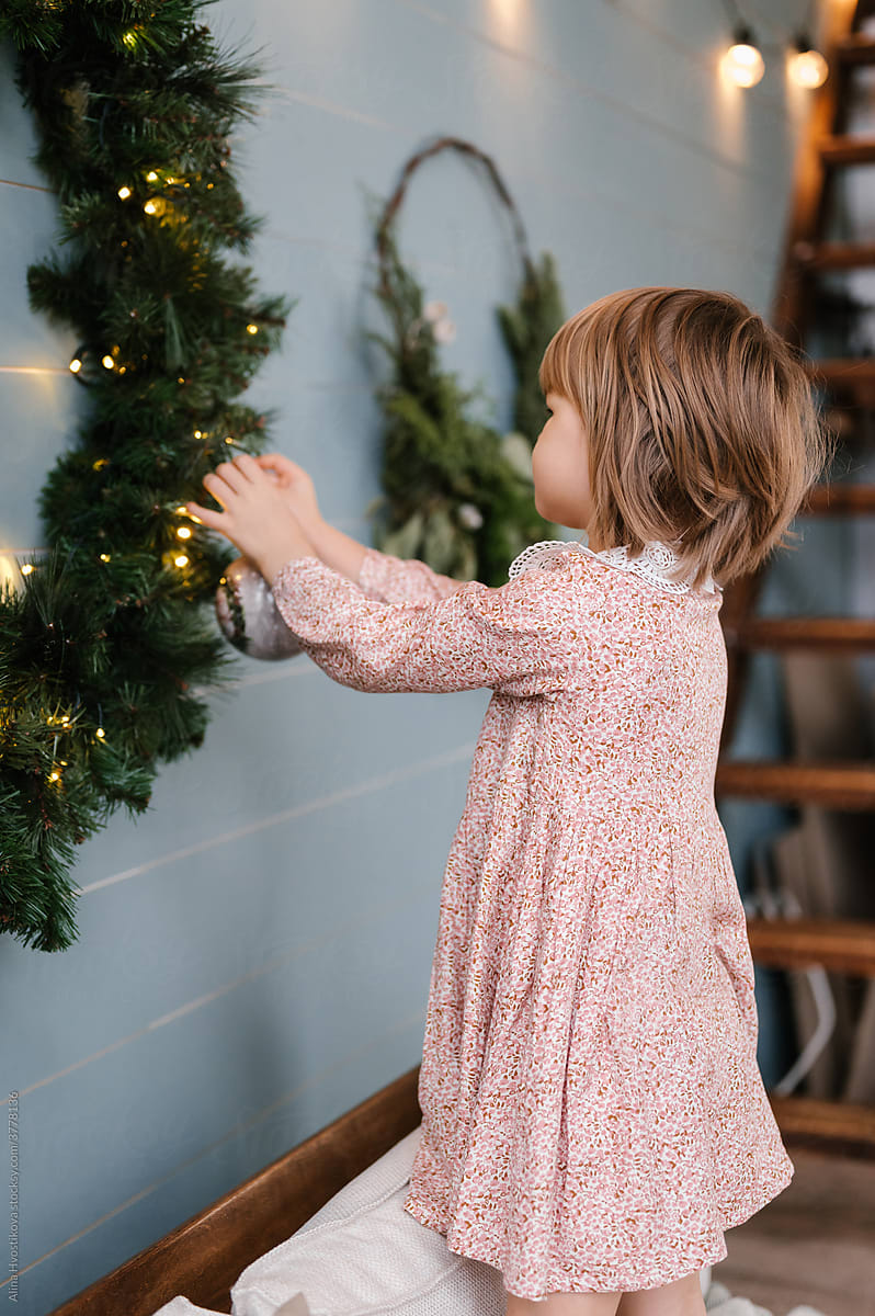 Girl decorating Christmas wreath with bauble