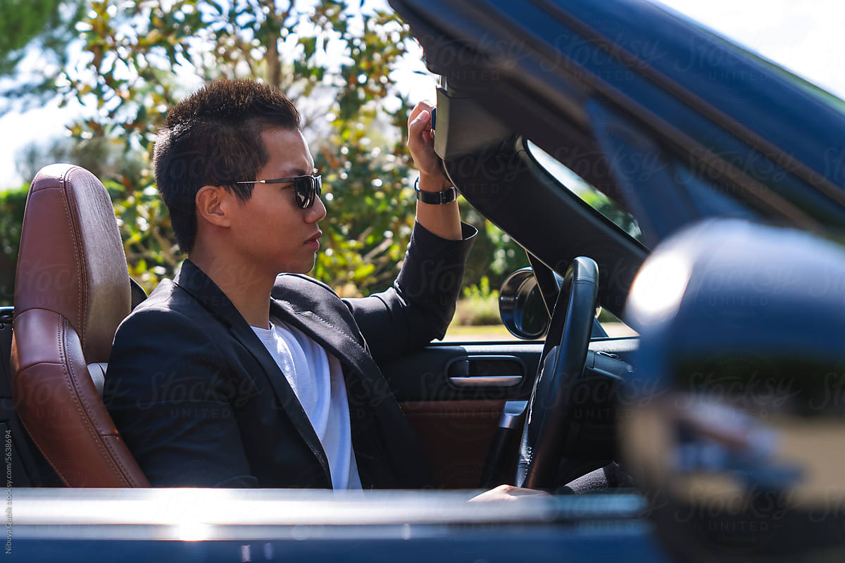 Handsome young businessman in his black convertible car ready to drive
