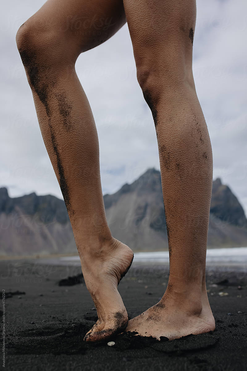 Vertical photo of woman\'s feet Walking On the black Beach