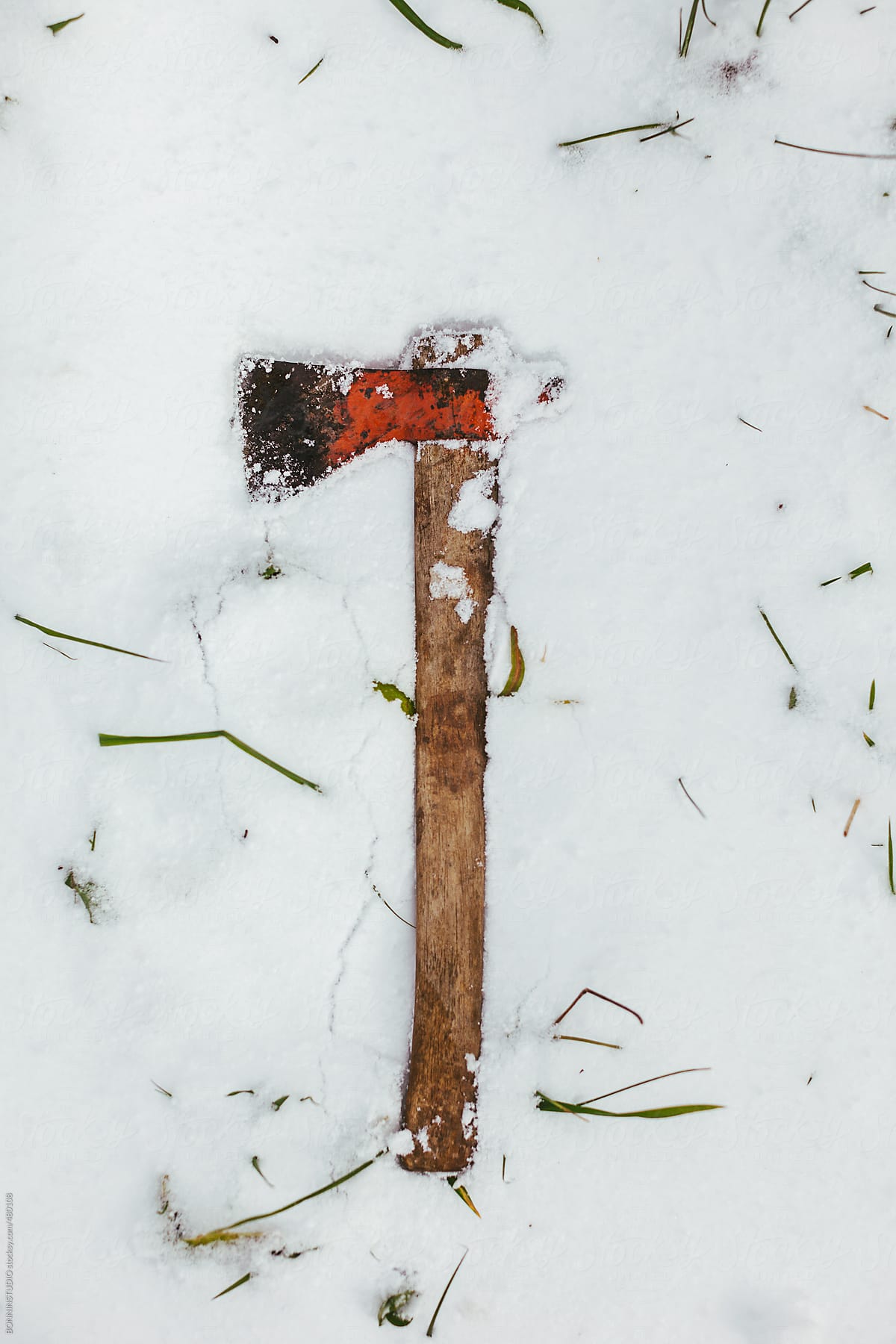 Axe on snow covered grass in winter.