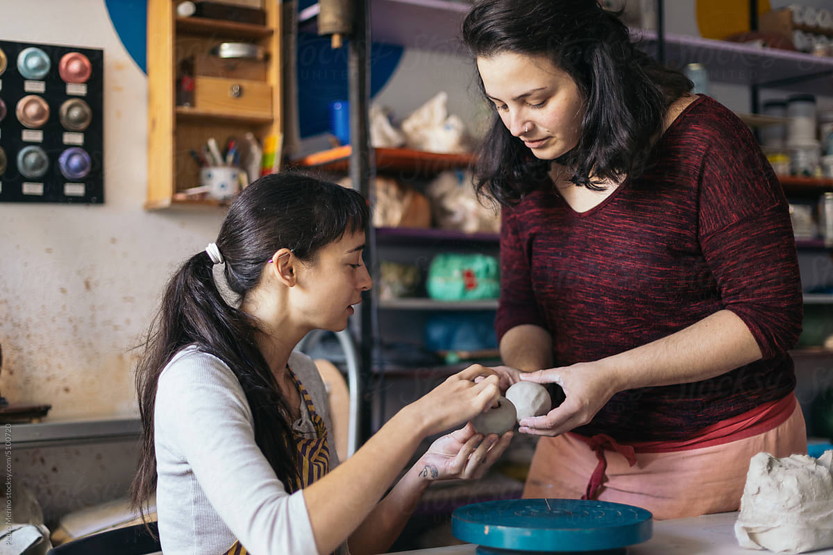 Pottery artisan teaching a woman to work the clay